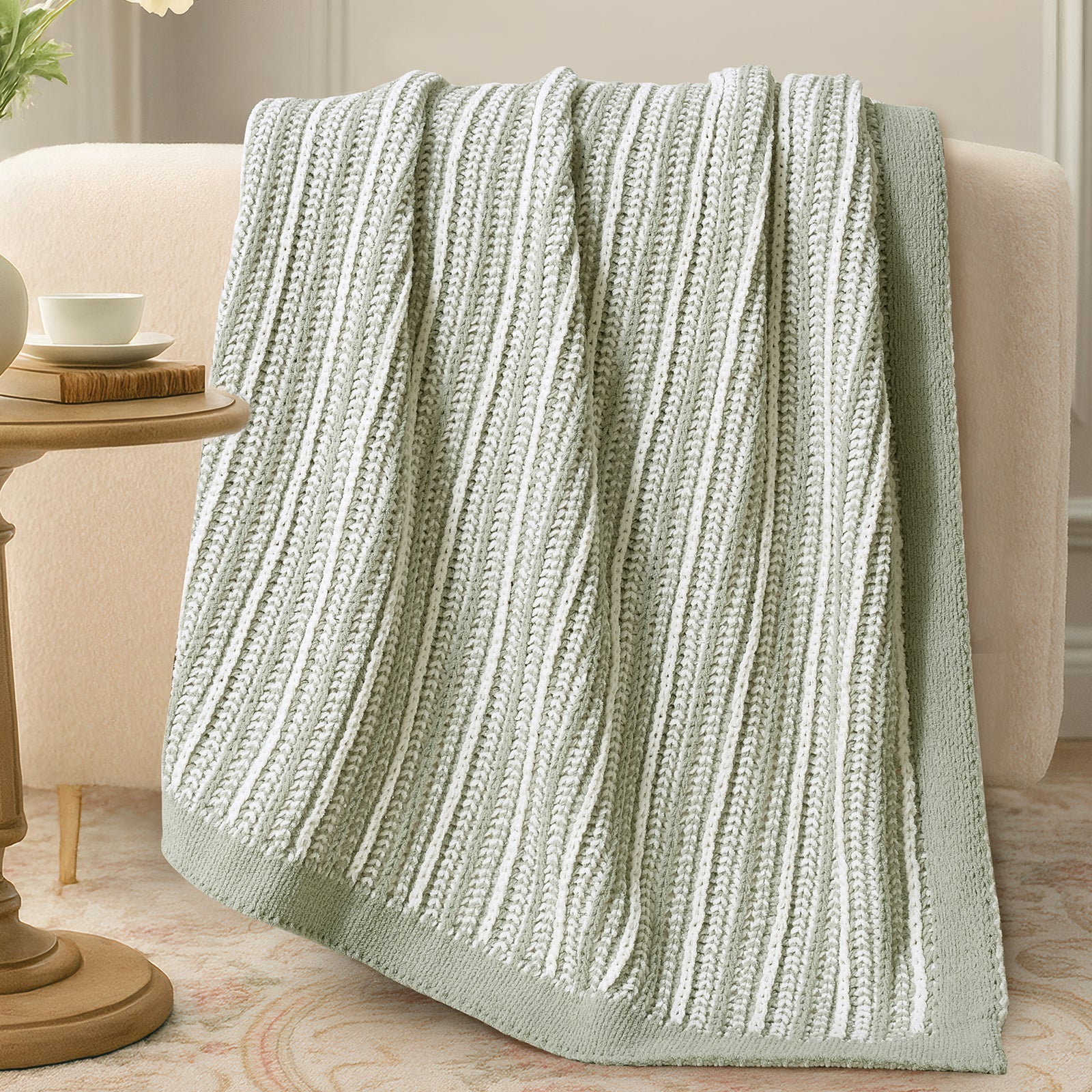 Knitted blanket draped over a sofa in a cozy living room setting. #color_Sage Green