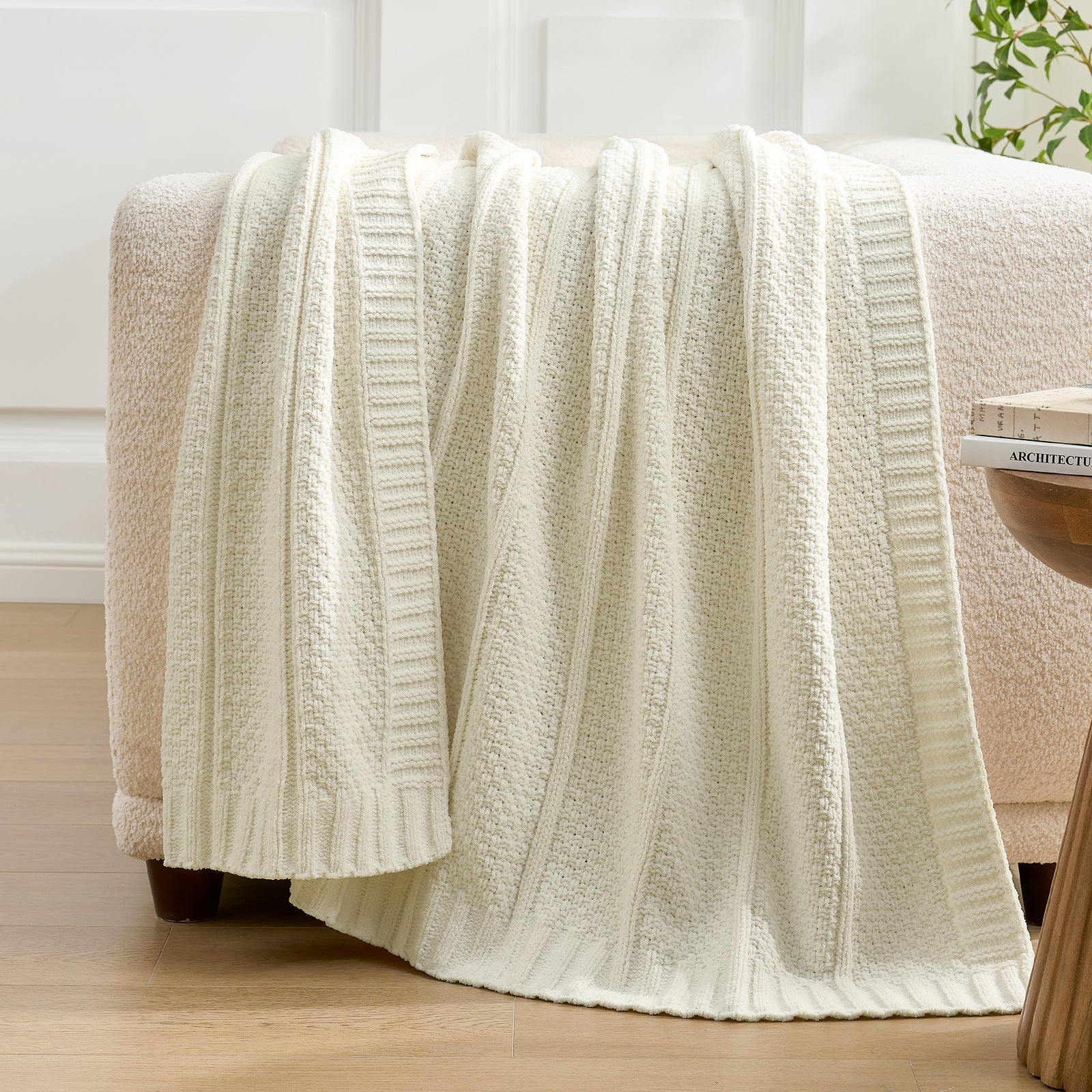 Snuggle Sac ivory textured blanket draped over a chair in a room with white walls and a plant. #color_Ivory