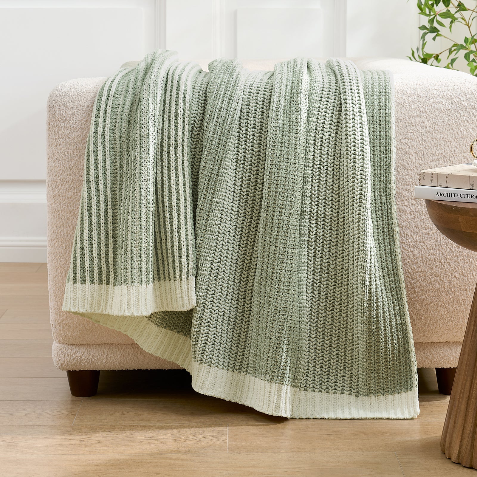 Snuggle Sac green and white striped blanket draped over a beige armchair in a room with wooden flooring. #color_Two-tone Green