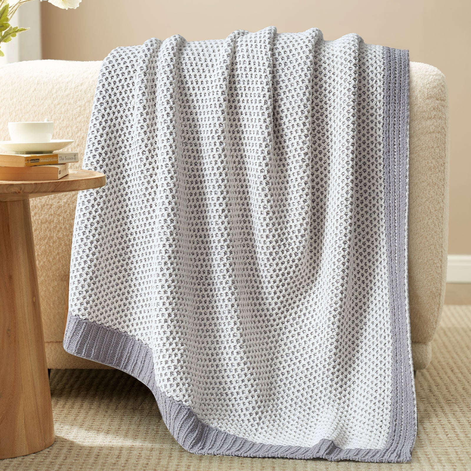 Gray textured blanket draped over a chair in a cozy living room setting. #color_Gray&White
