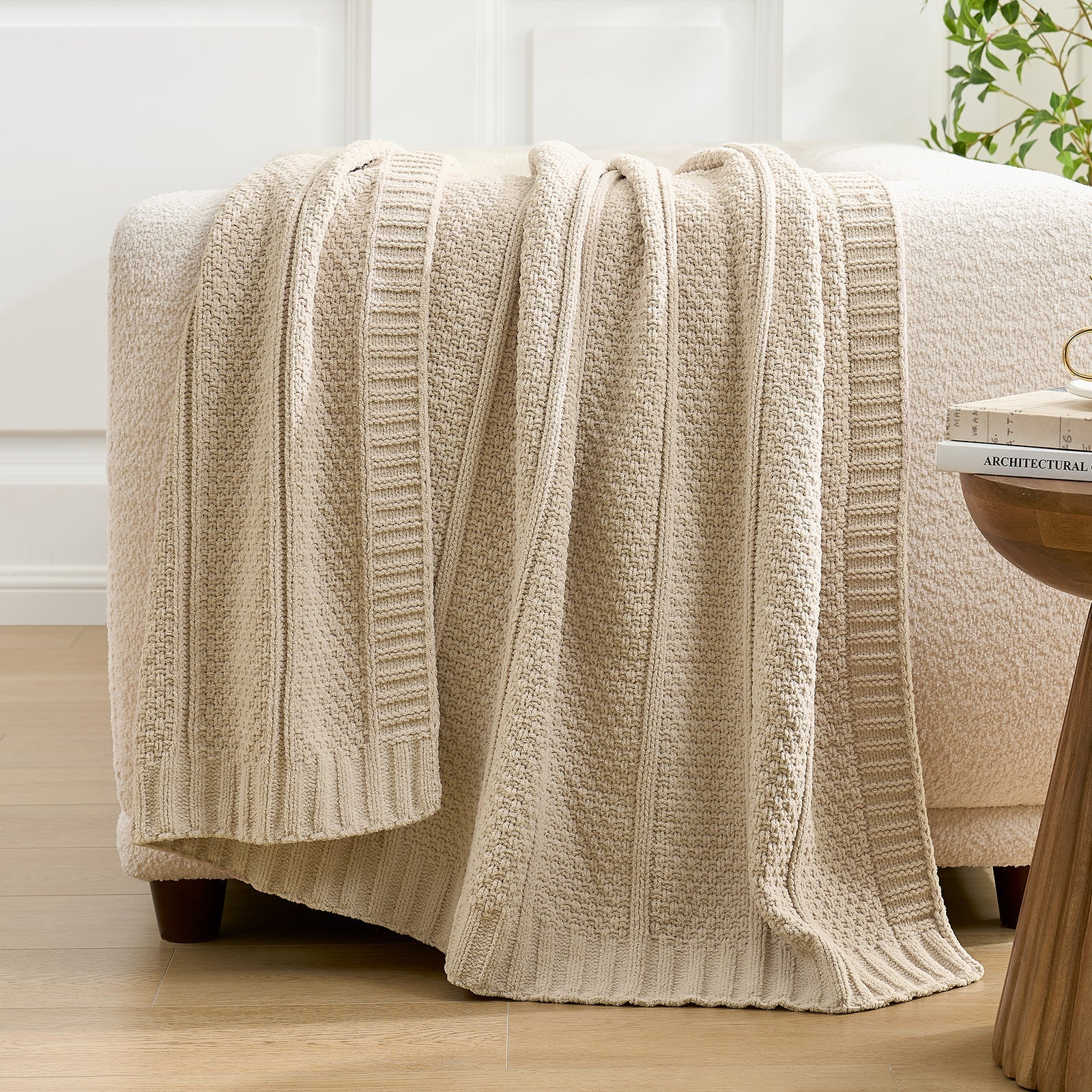 Snuggle Sac beige textured blanket draped over a white ottoman with a plant in the background. #color_Beige
