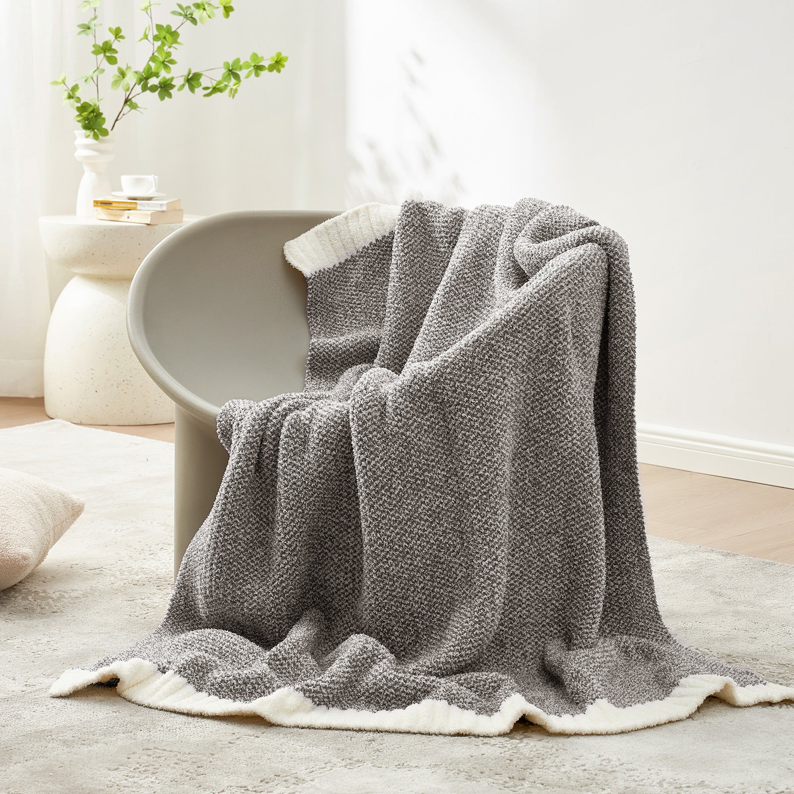 Gray textured blanket draped over a chair in a cozy living room setting.  #color_Dark Grey