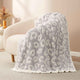 Reversible Leopard Feather Yarn Knit Throw Blanket on a beige couch in a bright room #Color_Leopard Grey